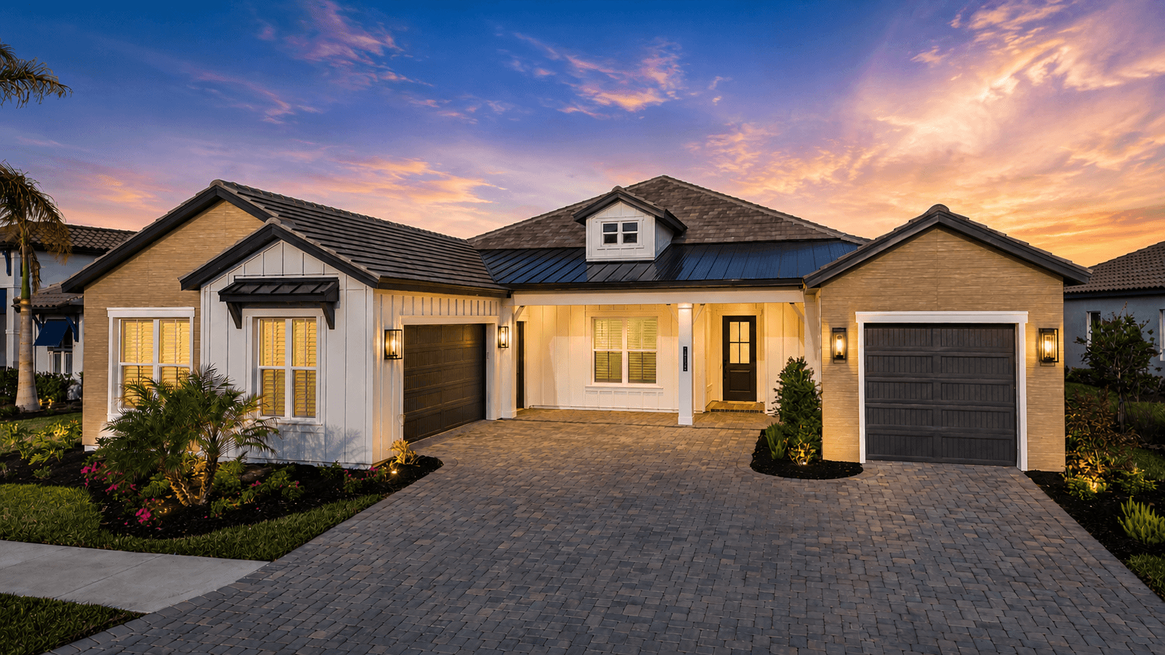 A Sam Rodgers home glowing at twilight under a pink Gulf Coast sky, paver drive leading to the front porch